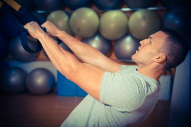 Genç adam bir spor salonunda trx devreye girer