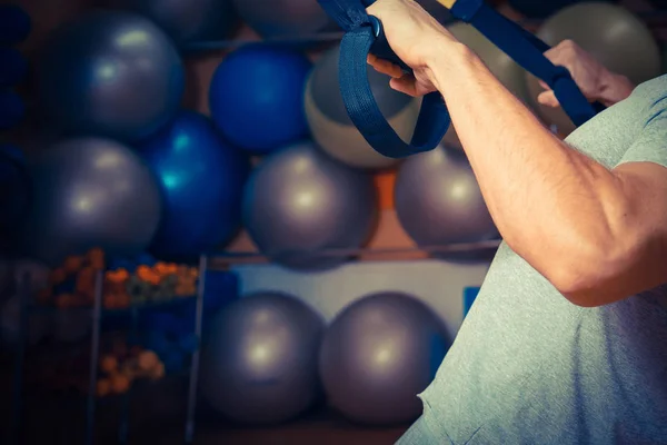 Young man is engaged in a gym in the trx — Stock Photo, Image