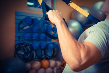 Genç adam bir spor salonunda trx devreye girer