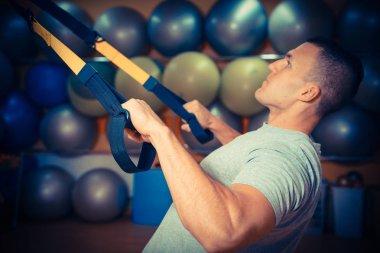Genç adam bir spor salonunda trx devreye girer