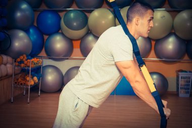 Genç adam bir spor salonunda trx devreye girer