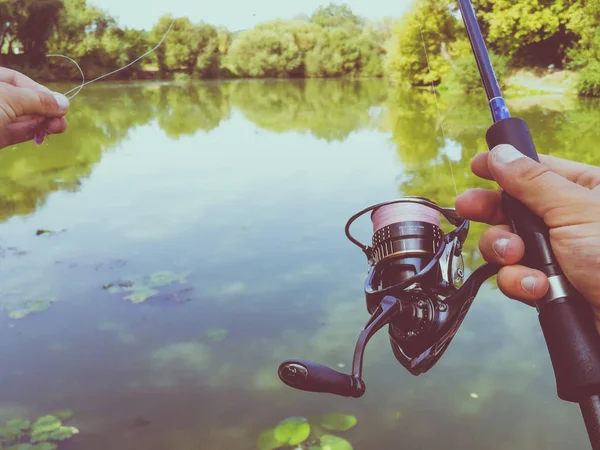 Une main de pêcheur avec une canne à pêche — Photo