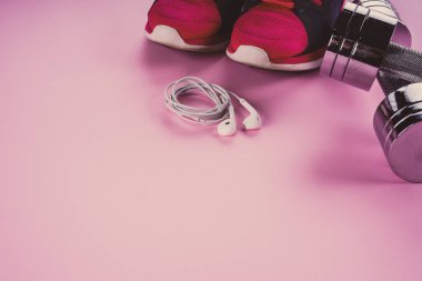 spor konsepti: spor ayakkabıları, halter, pembe backgr kulaklık