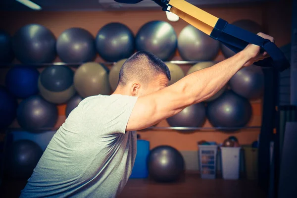 Giovane è impegnato in una palestra nel trx — Foto Stock