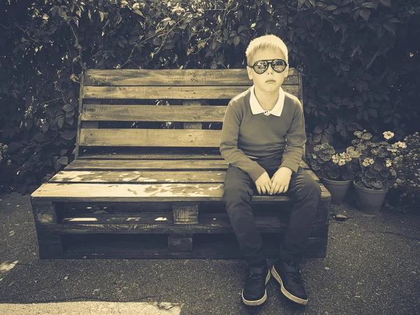 şık çocuk ahşap bir bankta oturur