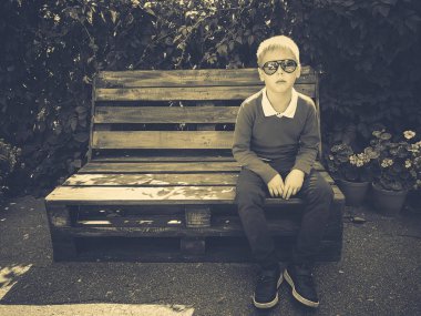 şık çocuk ahşap bir bankta oturur