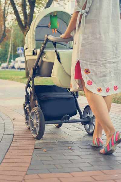 Moeder met een wandelwagen op een wandeling — Stockfoto