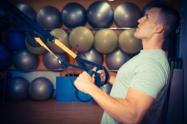 Genç adam bir spor salonunda trx devreye girer