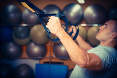 Genç adam bir spor salonunda trx devreye girer