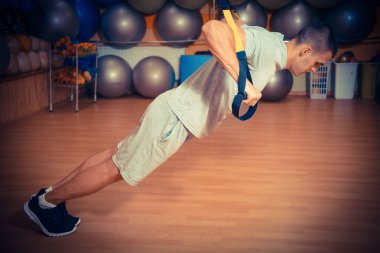 Genç adam bir spor salonunda trx devreye girer