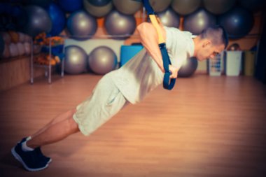 Genç adam bir spor salonunda trx devreye girer