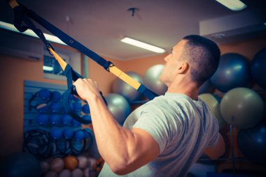 Genç adam bir spor salonunda trx devreye girer