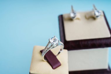 Kutudaki yüzük seti ve mavi arka plandaki küpeler