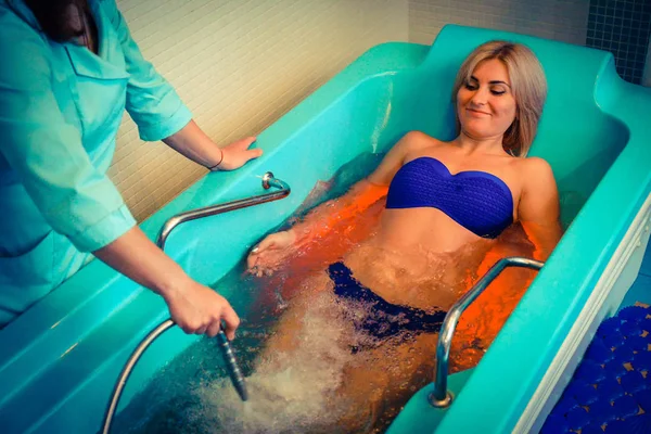 Blonde woman relaxing in spa salon during underwater massage