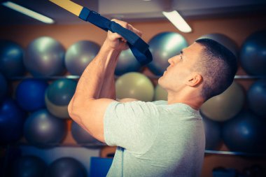 Genç adam bir spor salonunda trx devreye girer