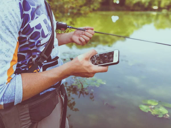 漁師は電話で夏に湖で釣りをしています — ストック写真