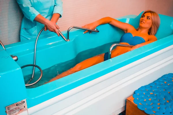 Blonde woman relaxing in spa salon during underwater massage