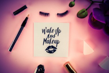 Pembe bir arka plan üzerinde çeşitli makyaj ürünleri