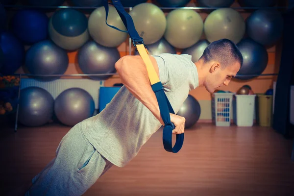 Young man is engaged in a gym in the trx — Stock Photo, Image