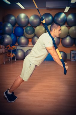 Genç adam bir spor salonunda trx devreye girer