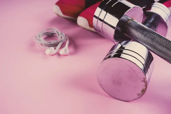 Concepto deportivo: zapatillas de deporte, mancuernas, auriculares en un fondo rosa — Foto de Stock