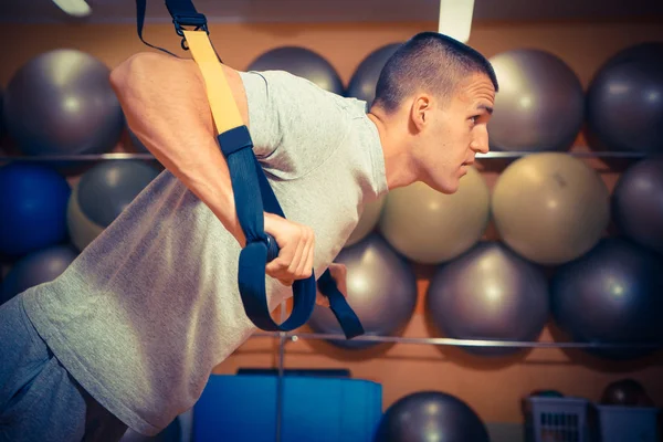 Genç adam bir spor salonunda trx devreye girer — Stok fotoğraf