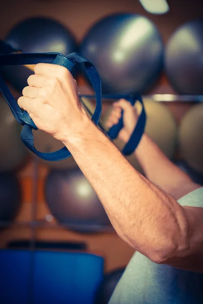 Young man is engaged in a gym in the trx — Stock Photo, Image