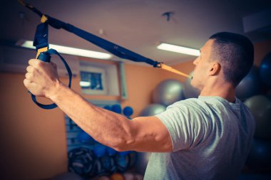 Genç adam bir spor salonunda trx devreye girer