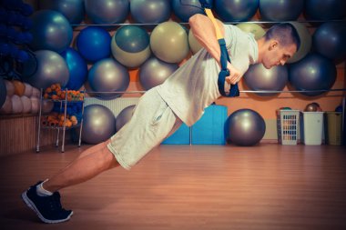 Genç adam bir spor salonunda trx devreye girer