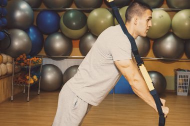 Genç adam bir spor salonunda trx devreye girer