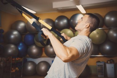 Genç adam bir spor salonunda trx devreye girer