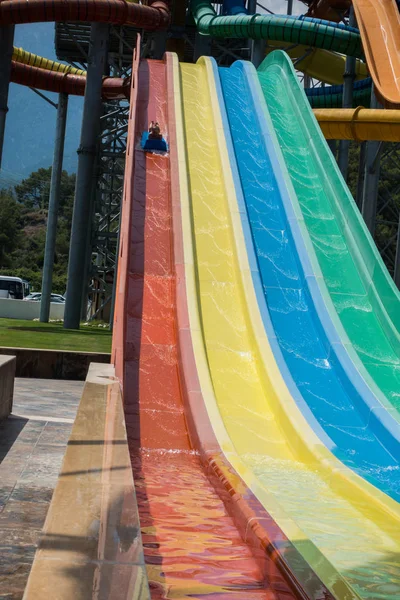 O menino monta um slide no parque aquático — Fotografia de Stock