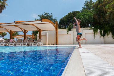 Çocuk havuza atlıyor.