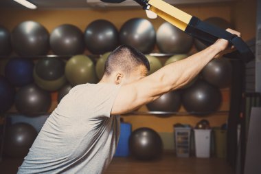 Genç adam bir spor salonunda trx devreye girer
