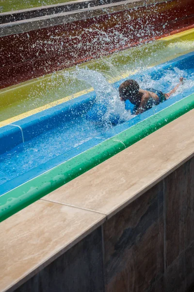 O menino monta um slide no parque aquático — Fotografia de Stock