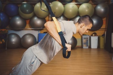 Genç adam bir spor salonunda trx devreye girer