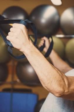 Genç adam bir spor salonunda trx devreye girer