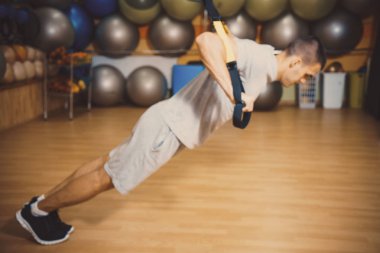 Genç adam bir spor salonunda trx devreye girer
