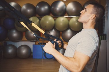 Genç adam bir spor salonunda trx devreye girer