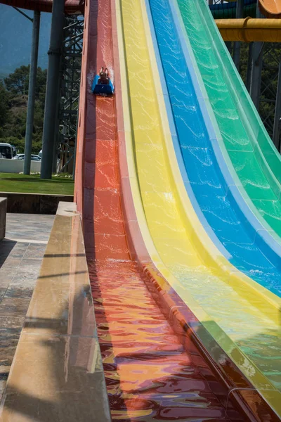 The boy rides a slide in the water park — Stock Photo, Image
