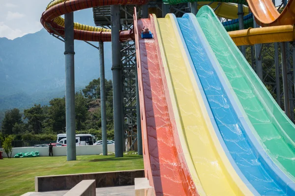 O menino monta um slide no parque aquático — Fotografia de Stock