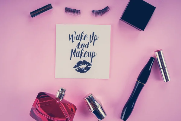 Various makeup products on pink background