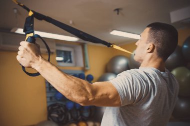 Genç adam bir spor salonunda trx devreye girer