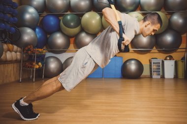 Genç adam bir spor salonunda trx devreye girer