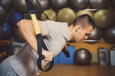 Genç adam bir spor salonunda trx devreye girer