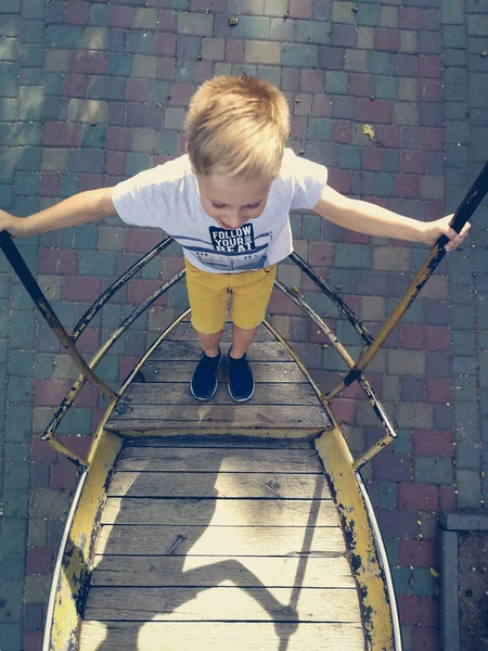 The boy is riding on a swing-boat — Stock Photo, Image