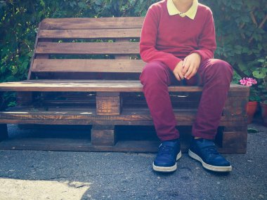 şık çocuk ahşap bir bankta oturur