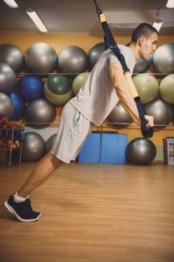 Genç adam bir spor salonunda trx devreye girer