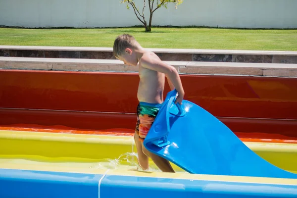 The boy rides a slide in the water park — Stock Photo, Image