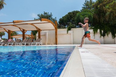 Çocuk havuza atlıyor.